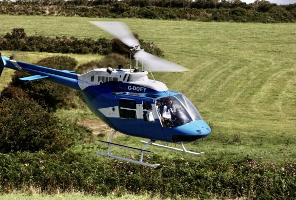 a blue and white helicopter flying over fields as part of a chopper experience