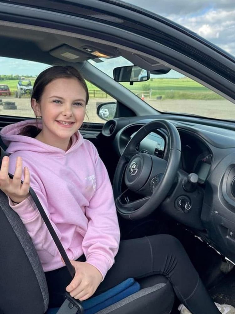 a young girl in the drivers seat of a car on a junior driving experience