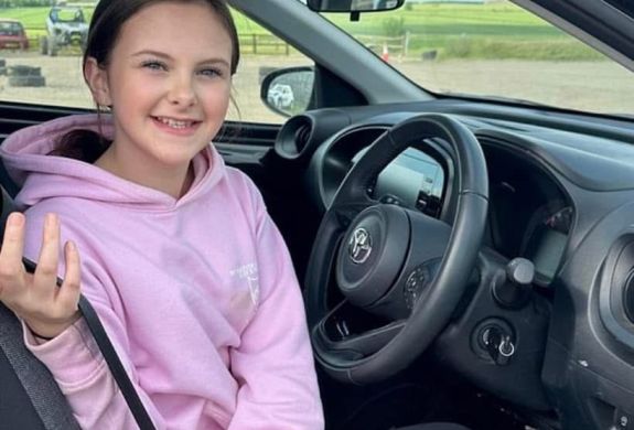 a young girl in the drivers seat of a car on a junior driving experience