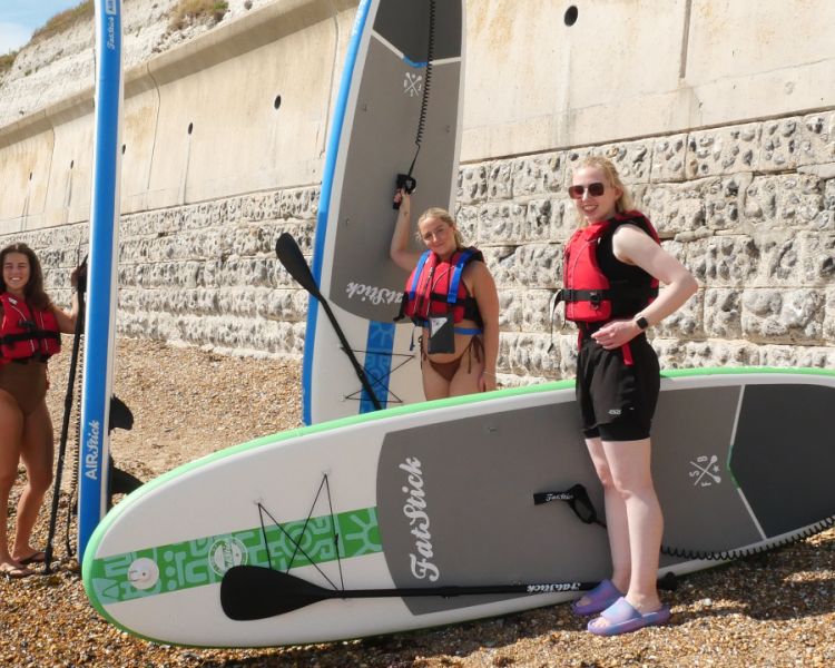 3 woman on the beach with paddle boards at SUP Hatt Adventures
