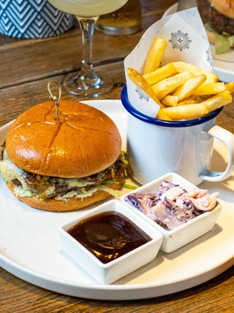 A close up of a burger and fries with condiments