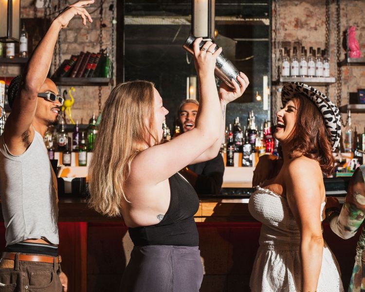 2 ladies at a bar shaking cocktails