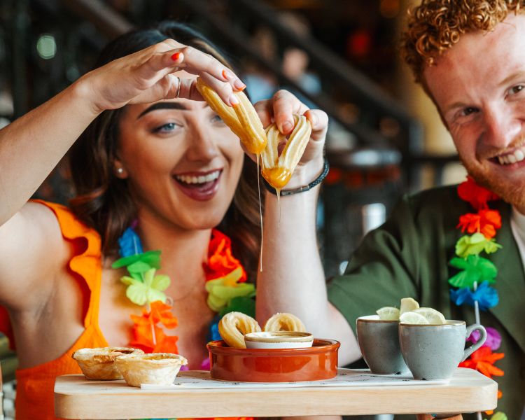 a man and a woman enjoying an afternoon tea with cuban inspired treats like churros