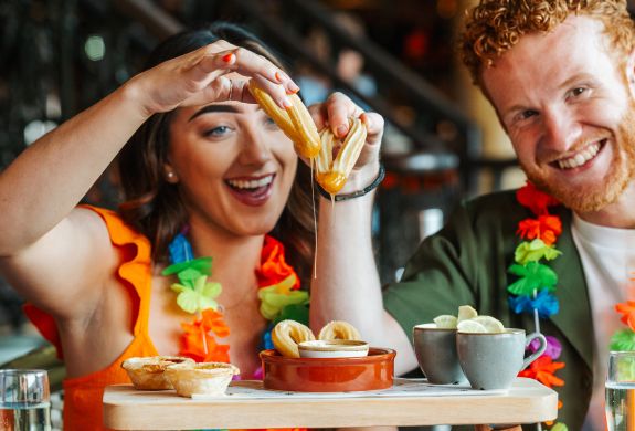 a man and a woman enjoying an afternoon tea with cuban inspired treats like churros