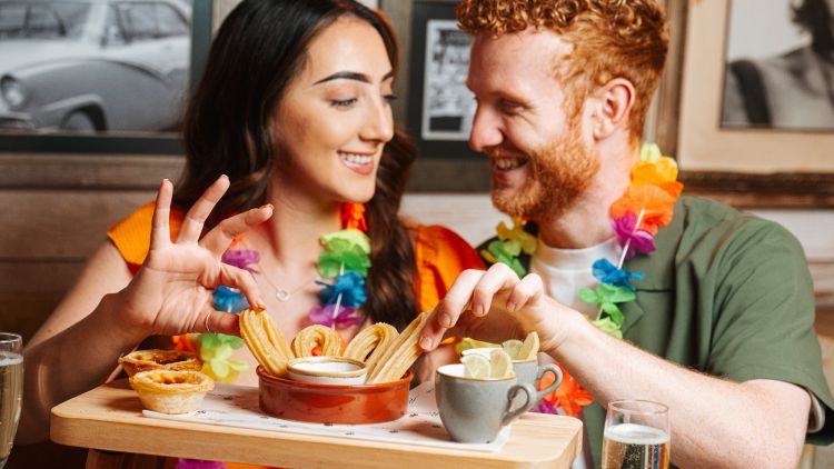 a man and a woman eating churros on a cuban inspired afternoon tea experience