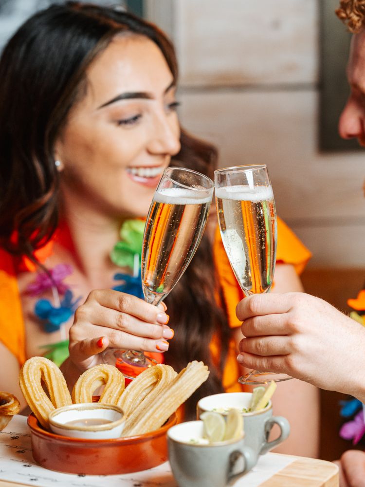 a woman and man with glasses of prosecco at a cuban inspired afternoon tea