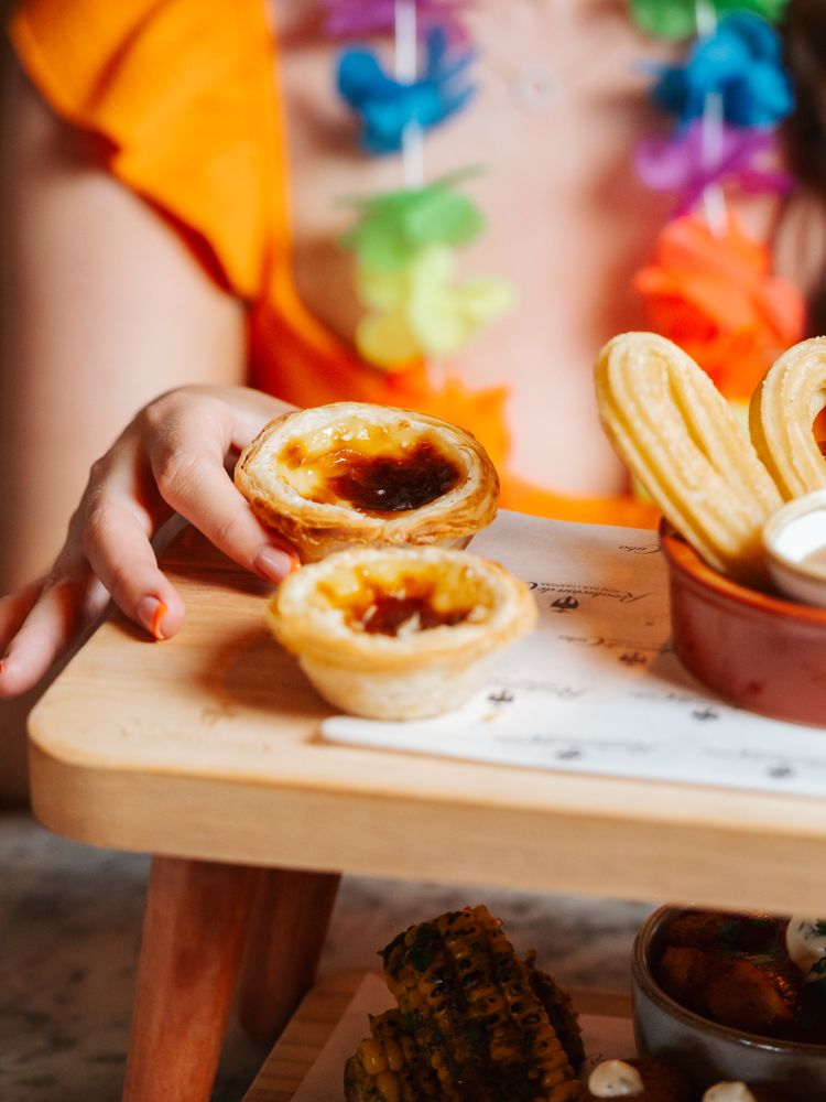a woman picking up a pastel de nata at a cuban inspired afternoon tea at revolucion de cuba