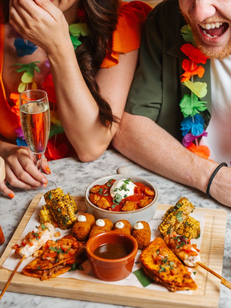 a man and a woman enjoying savoury food at a cuban inspired afternoon tea experience