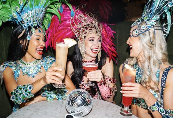 three ladies dressed in rio carnival dress enjoying cocktails at revolucion de cuba