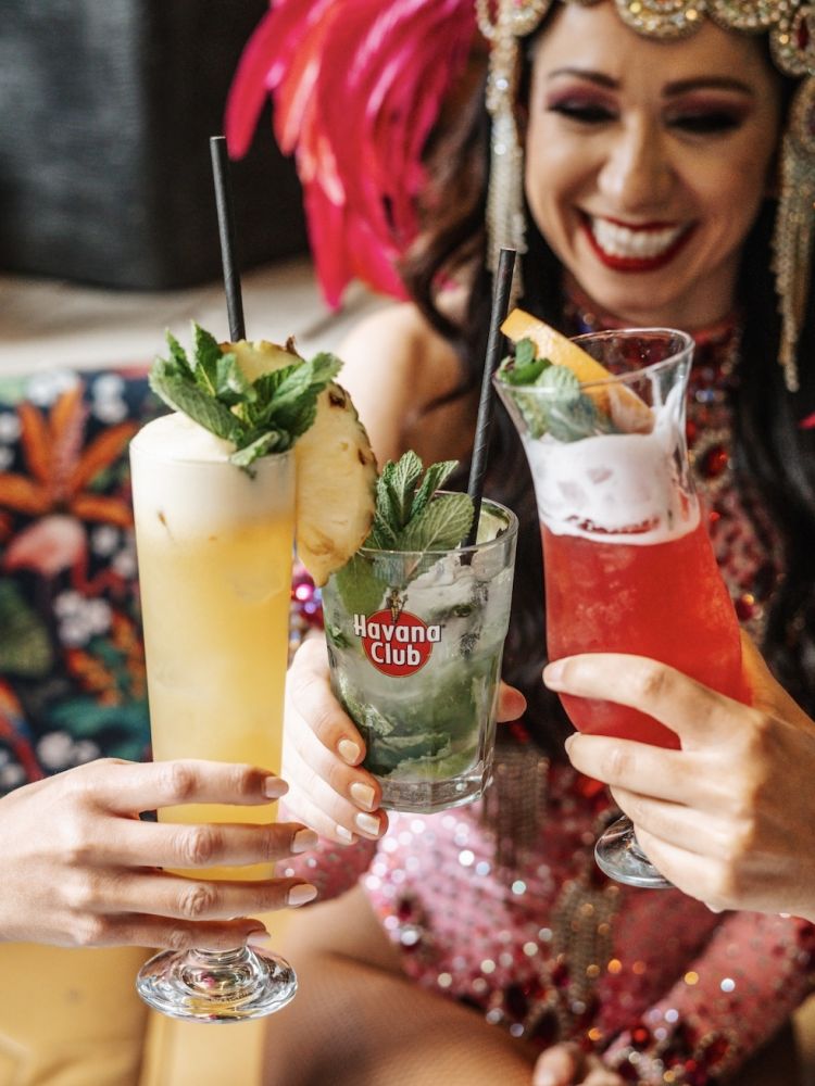 three ladies dressed in rio carnival dress enjoying cocktails on a tapas and cocktails experience at revolucion de cuba