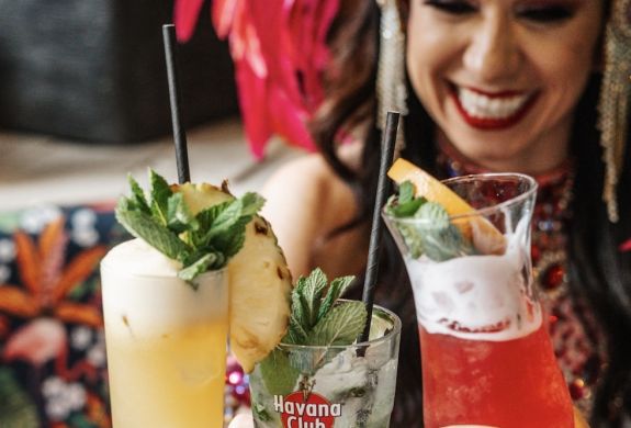 three ladies dressed in rio carnival dress enjoying cocktails on a tapas and cocktails experience at revolucion de cuba