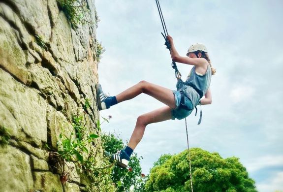 a girl abseiling down a rock face in wales