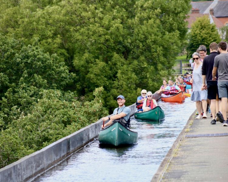 people in canoes going along an aqueduct in wales