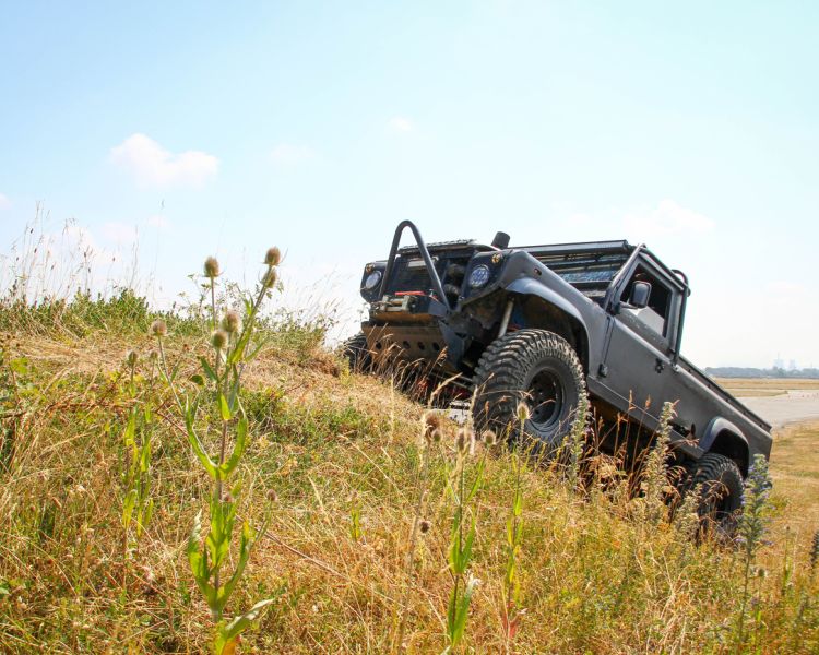 a mad max inspired land rover driving up a hill on a driving experience day