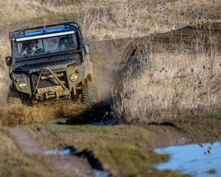 a mad max inspired land rover driving off road through muddy terrain as part of a driving experience day