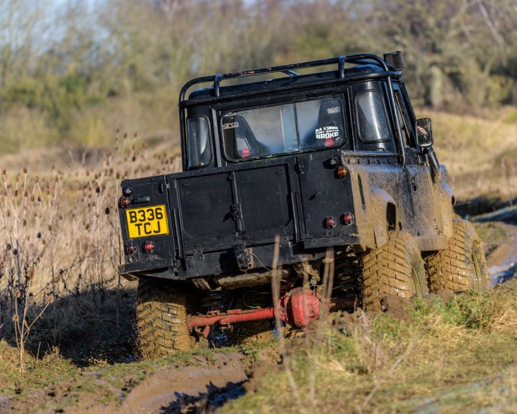 a mad max inspired land rover driving off road through muddy tracks as part of a driving experience day