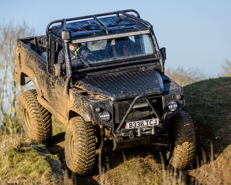 a mad max inspired land rover driving off road down a hill on a driving experience day