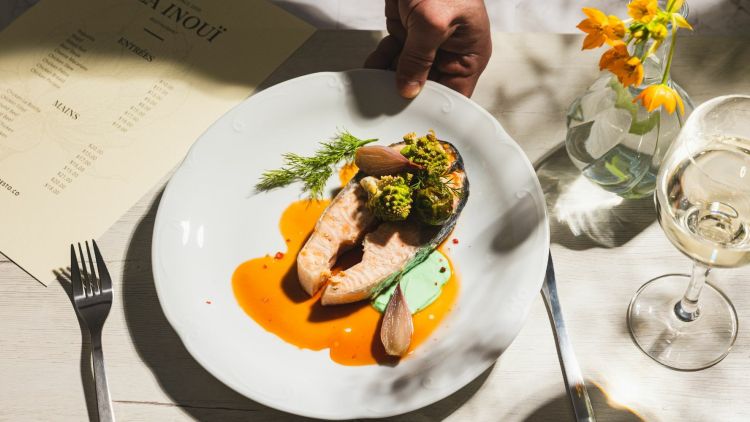 A fine dining restaurant scene of a plate of food being put on a table