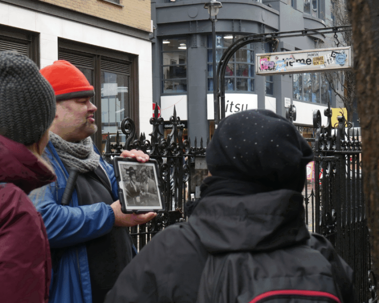 tour guide holding a photo talking to a group on the beatles walking tour in london