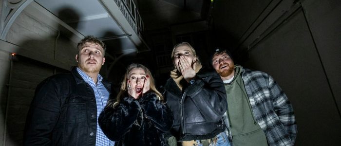 four young people looking scared on a ghost tour of a prison