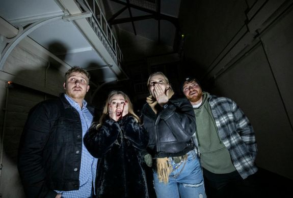 four young people looking scared on a ghost tour of a prison