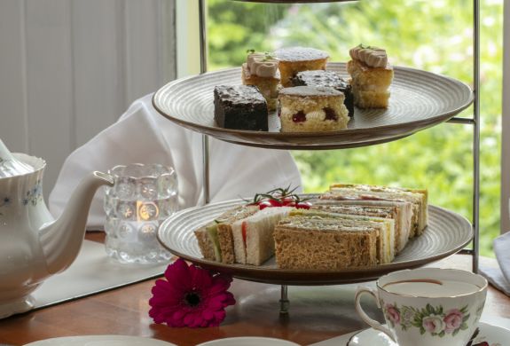 an afternoon tea set up on a cake stand with cups of tea on a table in front of a window at a hotel in ironbridge in shropshire