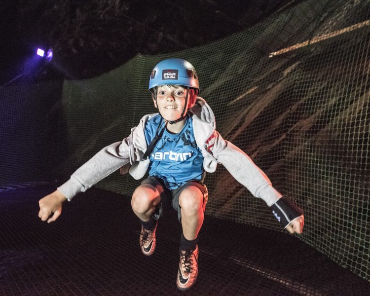 the trampolines built inside caverns at zip world bounce below lit up in pink