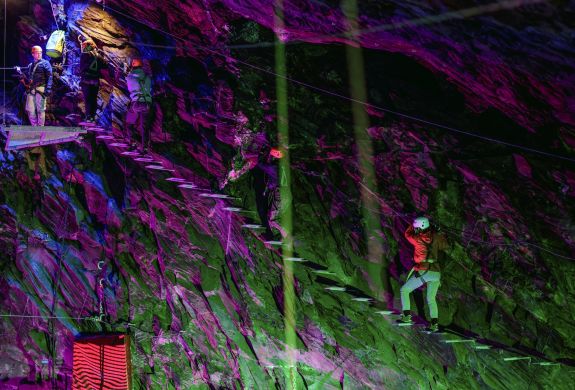 people climbing a ladder staircase underground in zip world caverns