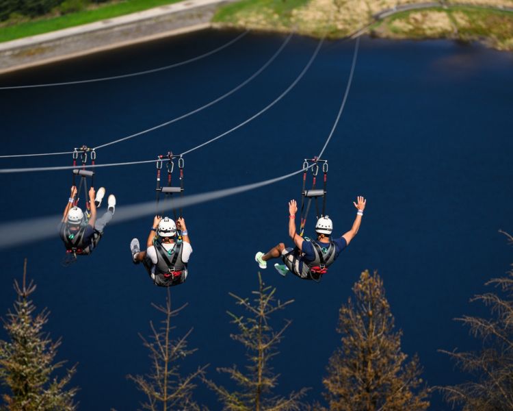 three people on the zip lines at zip world phoenix overlooking a lake