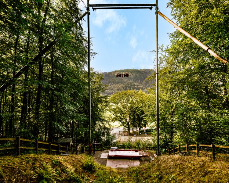 view of people on the zip world skyride in wales surrounded by trees