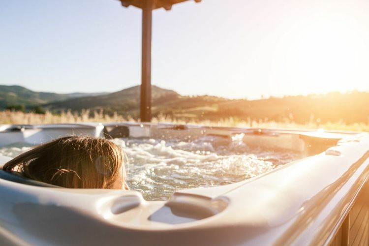 Lady in a hot tub with the sun setting