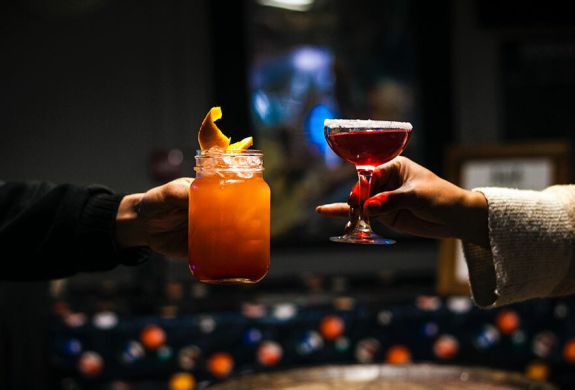 a shot of two arms each holding a different cocktail