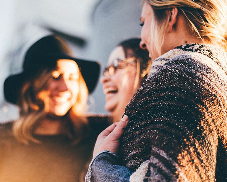 three women laughing in bright sunlight