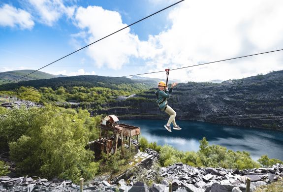 young girl on the zip world quarry flyer zip line going over the quarry