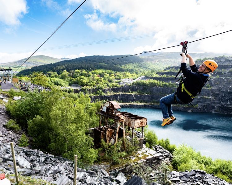 young woman on the zip world quarry flyer zip line going over the quarry