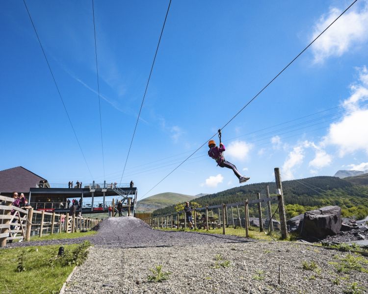 young girl on the zip world quarry flyer zip line going over the quarry