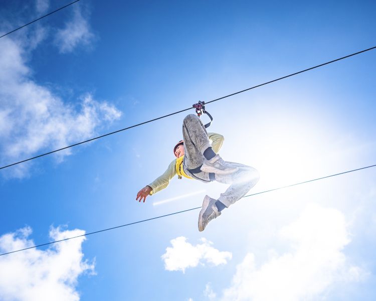 view of young girl on the zip world quarry flyer zip line against the blue sky