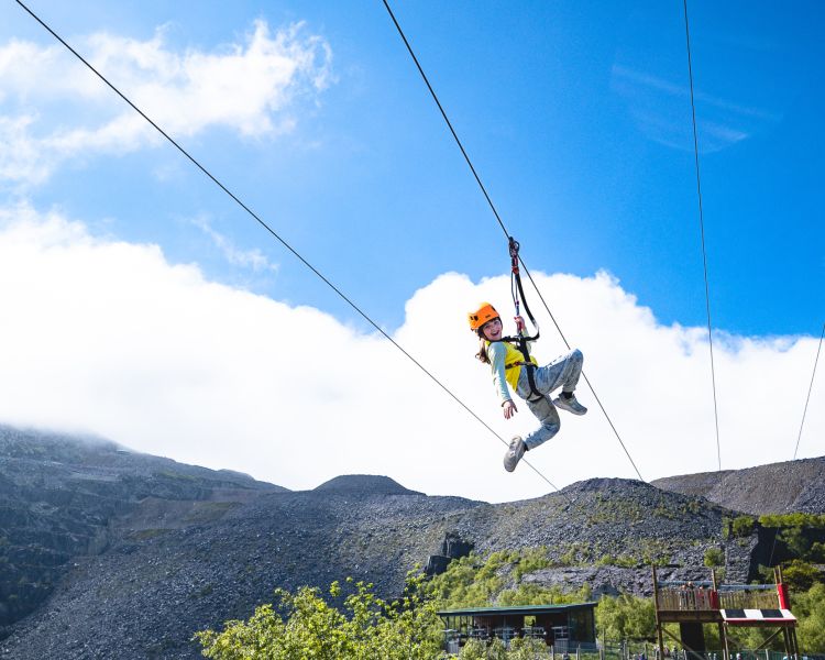young girl on the zip world quarry flyer zip line going over the quarry