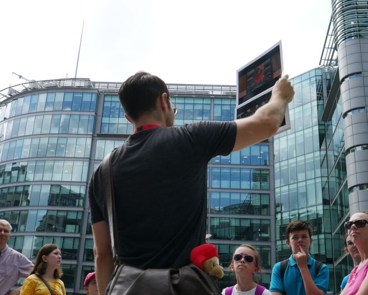 Guide talking to group of people while outside paddington station on a paddgington walking tour in london