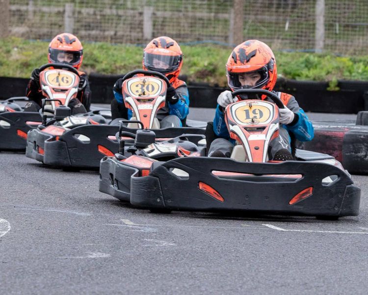 three people in a go kart race on a track