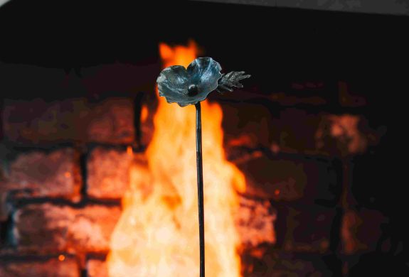 an iron poppy in front of an open fire made on a blacksmith poppy making experience