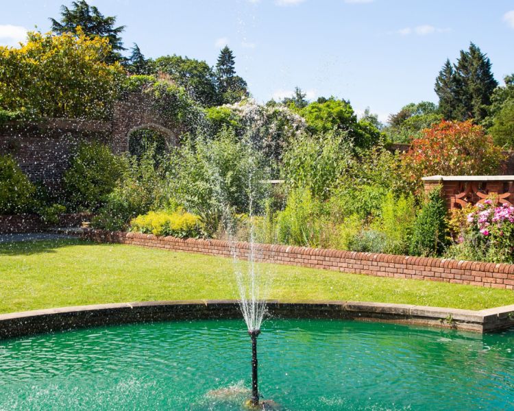 a fountain in the gardens of a country house hotel in hertfordshire