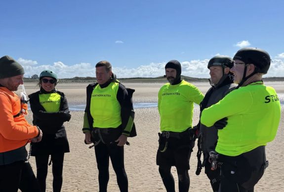 a group of students listening to an instructor on the beach on a land kitesurfing lesson