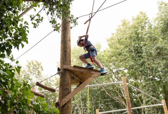 young boy on an aerial assault course high in the treetops