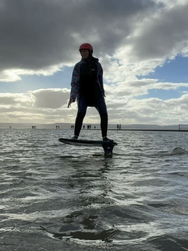 woman standing on a pump foil board in the sea on a pump foil lesson