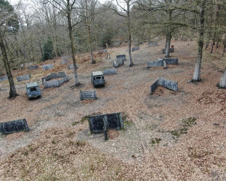 a view from above of a woodland paintball site with wooden huts and barriers