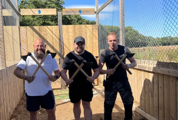 three men posing for photo holding axes on an axe throwing experience in tunbridge wells in kent