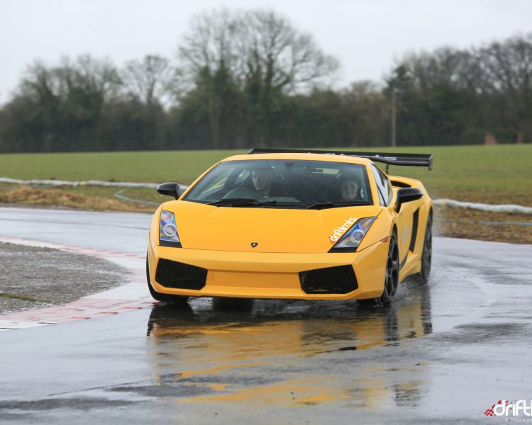 a yellow supercar being driven round a bend on a race track