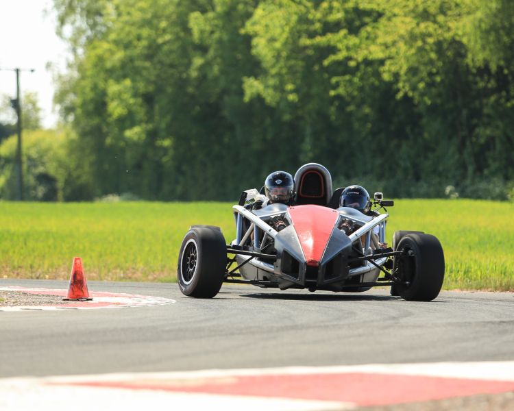 a black and red race car being driven round a bend on a race track