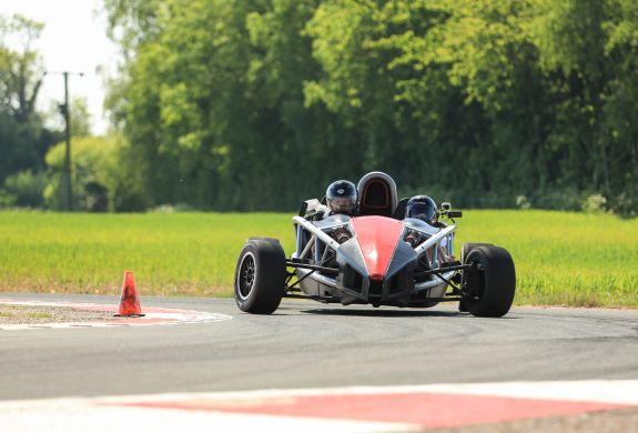 a black and red race car being driven round a bend on a race track